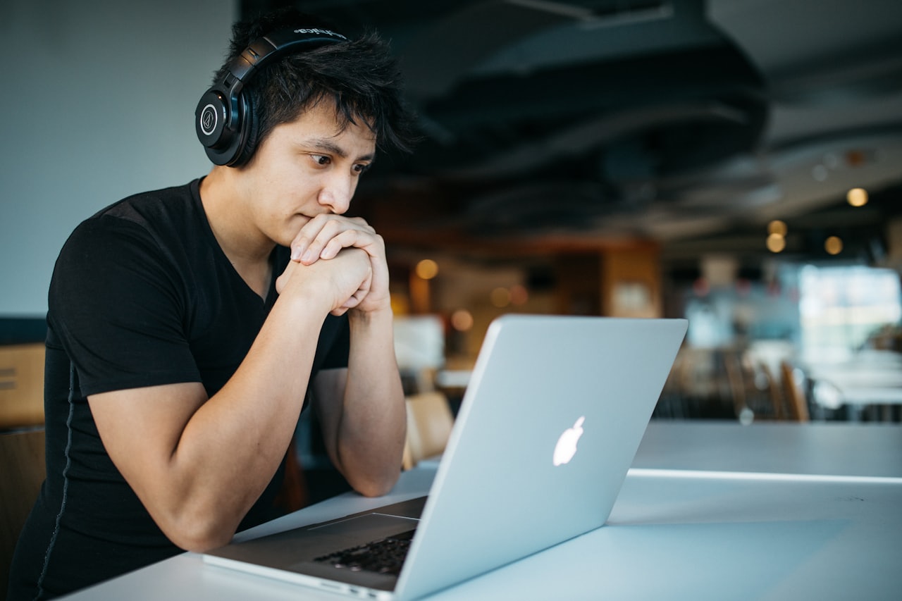 Focused person working on a laptop, wearing headphones
