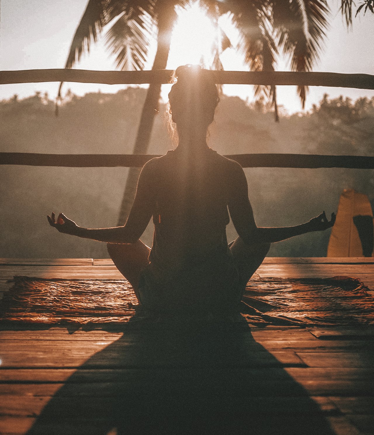 Person meditating facing the sunrise